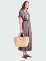 Bolso tipo shopper de gran tamaño, confeccionado en rafia natural con detalles de cuero en tono beige claro. Presenta asas superiores de cuero, cierre de broche tipo toggle con tira de cuero y estructura rígida.