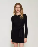 Remera negra de punto con textura acanalada, cuello redondo y mangas largas. Presenta un lazo en la cintura que se ata en la espalda.