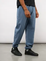 Pantalón de jogging de felpa con friza, color gris, con cintura elástica, bolsillos laterales y puños en los tobillos. Presenta un parche con el logo de Umbro en la parte superior delantera.