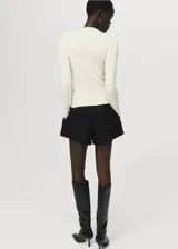 Cardigan de tejido de punto fino color blanco, con cuello redondo, manga larga y cierre frontal abotonado con diseño entallado.