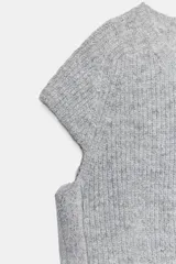 Jersey de punto gris jaspeado con cuello redondo y manga corta. Presenta detalles de encaje en los laterales.