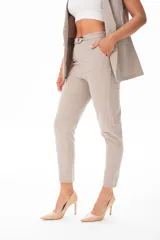 Pantalón de vestir color beige, con corte recto, bolsillos laterales y cinturón con hebilla metálica.