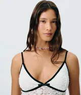 Body de encaje blanco con transparencia sutil, escote en V con ribete negro y un pequeño lazo decorativo al centro, breteles finos y diseño ajustado al cuerpo de la marca Blue Steel.