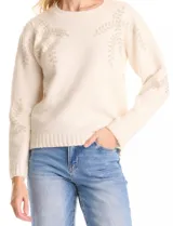 Buzo color beige de tejido suave con bordados florales de ramas y hojas en canutillos al tono en la parte delantera y mangas. Escote, puños y ruedo con terminación en rib acanalado.