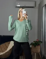 Sweater de punto color bordó con escote en V y detalle de strass aplicado en la parte frontal. Presenta mangas largas y corte holgado.