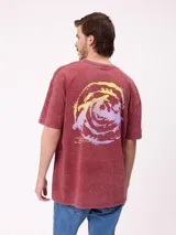 Remera de corte oversize color bordó con efecto lavado, manga corta y estampa gráfica circular en la espalda con diseño de olas en tonos amarillos y violetas.