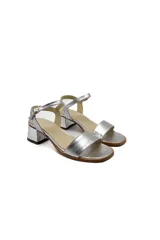 Sandalias plateadas de cuero con taco bloque bajo y tira delgada ajustable al tobillo.