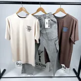 Remera marrón de mangas cortas con estampa en la espalda que incluye una flor azul, la frase "Boundless Art" y números.