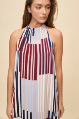 Vestido largo de silueta amplia y caída fluida, con escote halter fruncido y falda con recorte. Presenta diseño geométrico multicolor a rayas en tonos bordó, azul, celeste y beige.