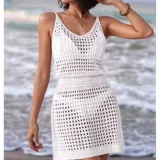 Vestido corto de playa tejido con diseño calado, sin mangas y cuello redondo. Presenta un calce adaptable al cuerpo.