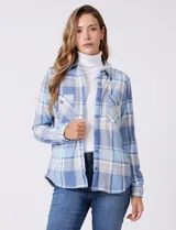 Sobrecamisa de tejido soft con estampado de cuadros en tonos azules y blancos. Presenta cuello con solapa, cierre frontal con botones, bolsillos aplicados en el pecho y mangas largas con puños abotonados. El interior cuenta con un acabado afelpado.