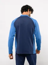 Buzo de entrenamiento Umbro del Club Nacional de Football, con medio cierre frontal, cuello alto y mangas largas. Presenta el logo de la marca y el escudo del club en el pecho.