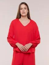 Blusa azul de corte holgado y fluido, con escote en V y mangas largas raglán que presentan detalles de calados con forma de flores y puños elastizados.