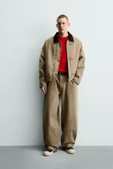 Cazadora de corte relajado confeccionada en algodón con efecto lavado. Presenta cuello de solapa en contraste de color negro, cierre frontal con cremallera oculta y alamares metálicos, bolsillos laterales de vivo y mangas largas.