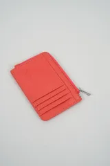 Billetera pequeña color negro con cierre de cremallera plateado y apliques de tachas metálicas redondas en la parte frontal.