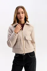 Campera corta de paño color negro, con cierre frontal metálico, cuello camisero y bolsillos frontales con solapa y botón metálico.