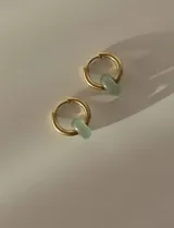 Aros de acero quirúrgico dorados en forma de argolla con dijes de piedra natural negra en forma de dona, desmontables.