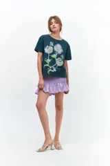 Remera lila de algodón con estampado de flores en tonos naranja y rosa.