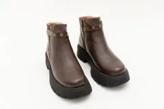 Borcego de cuero marrón con apliques de ojales metálicos y suela track.