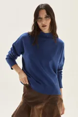 Polera de tejido de punto color azul, con cuello alto, manga larga y puños acanalados.