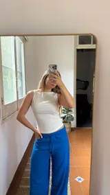 Top sin mangas de color crudo, confeccionado en tela elastizada con textura fruncida y cuello redondo.