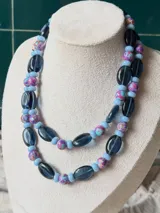 Collar de doble vuelta con cuentas de vidrio azul oscuro facetadas, abalorios celestes y cuentas esféricas multicolores con estampado abstracto en tonos rosados, celestes y morados.
