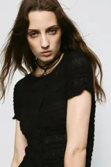 Top de punto negro con textura de nido de abeja, cuello redondo, mangas cortas y cierre frontal con botones.