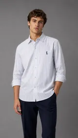 Camisa de manga larga con diseño de rayas verticales celestes sobre fondo blanco, cuello italiano y cierre frontal con botones. Cuenta con bordado sutil en el pecho.