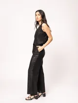 Pantalón de lino color beige, de tiro alto, pierna ancha y levemente acampanada. Tiene pinzas delanteras, elástico en la pretina trasera, cierre delantero y broche interno, bolsillos laterales y dobladillo invisible.