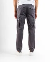 Pantalón cargo negro de corte slim, confeccionado principalmente en algodón con un pequeño porcentaje de spandex para elasticidad. Presenta múltiples bolsillos utilitarios con tapa y remaches de refuerzo.