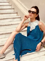 Vestido azul metálico con cuello plateado, sin mangas, corte recto, largo midi con flecos y tajos laterales.