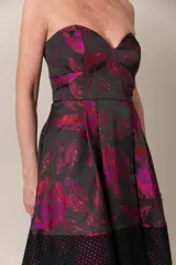 Vestido strapless negro con estampado de hojas fucsias y guarda calada negra en el bajo.