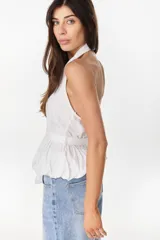 Blusa de cuello halter en color beige, con escote en V pronunciado, corte ajustado en el torso y detalle de volados fruncidos en la cintura con un lazo lateral ajustable.