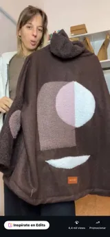 Campera de diseño artesanal en color marrón, confeccionada con texturas tipo corderito. Presenta un diseño abstracto en la espalda compuesto por parches geométricos en tonos blanco, rosado y marrón. Posee cuello alto y corte holgado.