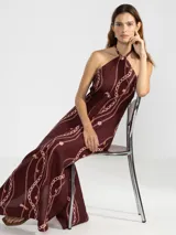 Vestido largo marrón con estampado de cadenas y flores rosadas, escote halter con cordón ajustable y insignia Polonio removible.