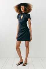 Vestido corto de denim azul con cuello mao, cierre tipo alamar en el pecho, mangas cortas abullonadas y fruncido lateral.