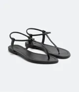 Sandalia plana minimalista de dedo, color negro, con tira fina y cierre elástico en el talón.