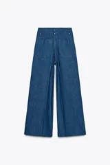 Jeans de tiro alto y pierna ancha de Zara, confeccionados en mezcla de algodón color beige. Presentan cintura con trabillas, bolsillos de parche en la espalda, costuras frontales marcadas y cierre delantero con cremallera, botón y gancho metálico.