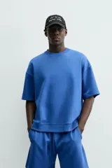 Sudadera de manga corta color marrón oscuro, con cuello redondo y bajo acabado en rib. Presenta un corte relajado y holgado (boxy fit).