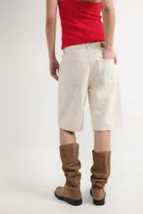 Bermuda de denim color blanco off-white, de tiro alto y corte recto y holgado, con bolsillos laterales y traseros.