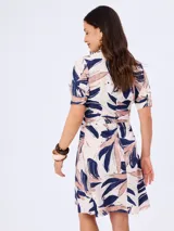 Vestido midi con estampado abstracto de hojas en tonos azul marino y beige, cuello en V con solapa, mangas cortas y lazo ajustable en la cintura.