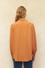 Camisa blanca de mangas abullonadas con sutiles plisados frontales, cuello clásico y corte relajado.