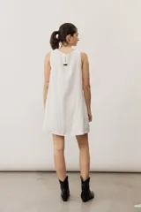 Vestido corto blanco sin mangas, con cuello redondo y detalle de nudo drapeado en el lateral.