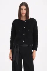 Saco de punto negro con diseño bordado floral en relieve, cuello redondo, cierre frontal con botones metálicos y bolsillos frontales decorativos.