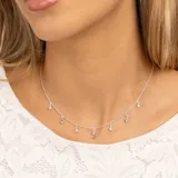 Collar plateado con cadena de eslabones y dijes colgantes: estrellas con topacios blancos, piedras redondas de topacio azul y una piedra ovalada de topacio azul en el centro.