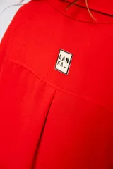 Camisa roja amplia de manga larga con ruedo curvo.