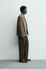 Pantalón de corte relajado confeccionado en una mezcla de algodón y lino. Presenta cintura elástica con cordón ajustable, bolsillos laterales y bolsillos traseros de vivo.