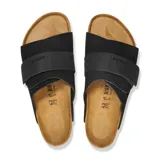 Sandalia Birkenstock modelo Kyoto, color negro, confeccionada en gamuza con una banda ancha ajustable mediante cierre de velcro y detalles de remaches metálicos. Presenta plantilla anatómica de corcho y suela de goma.