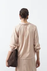 Camisa negra de corte relajado y caída fluida, con cuello clásico, escote en V y cierre frontal con botones forrados. Presenta mangas largas con puños abotonados.