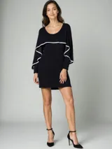 Vestido corto negro con escote redondo y mangas largas con volados blancos en los bordes.